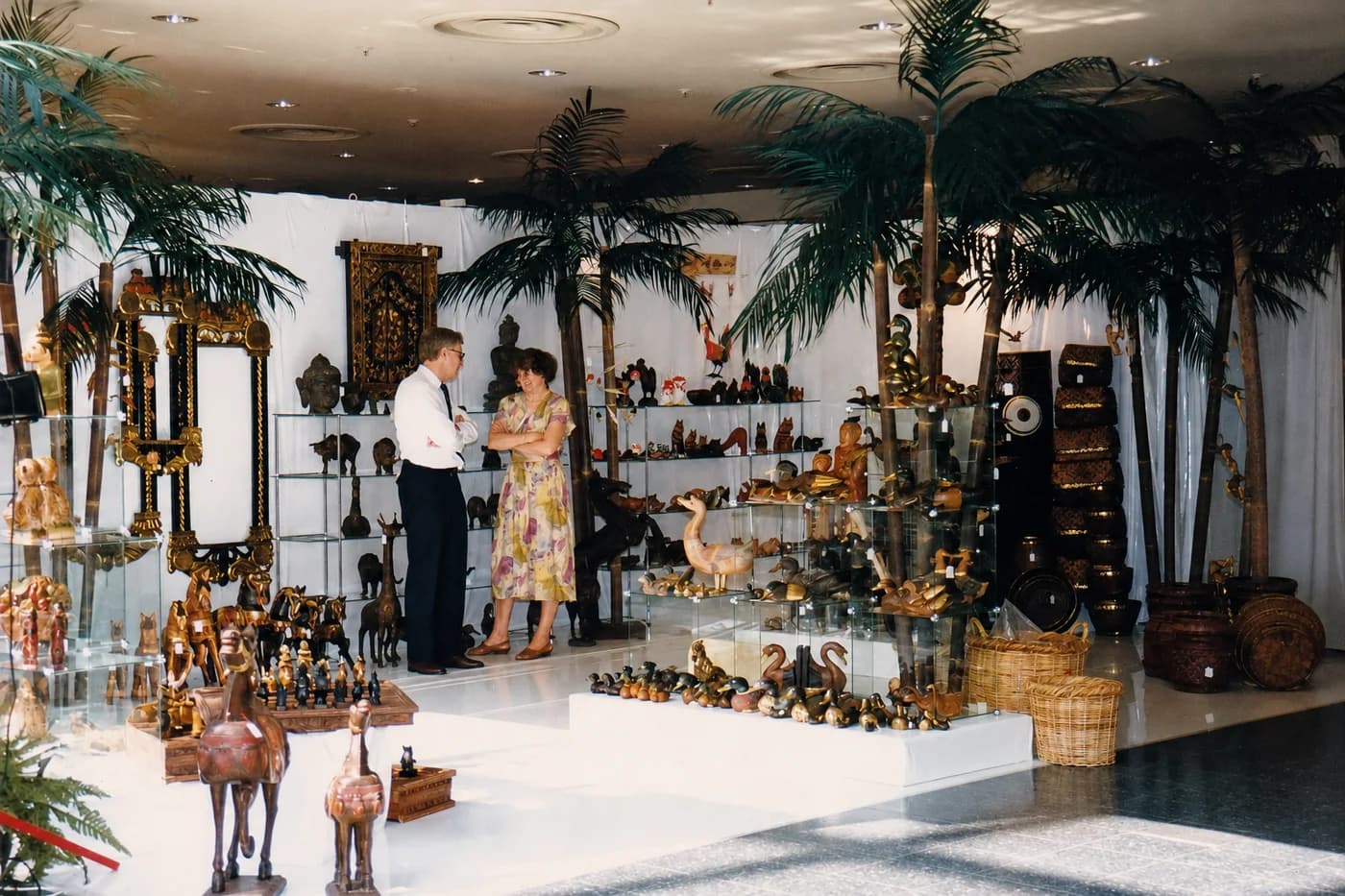Thomas Hoffmann and Arno Müller at the Tom's Company trade-fair stand in 1988, among hand-carved wooden animals and palms