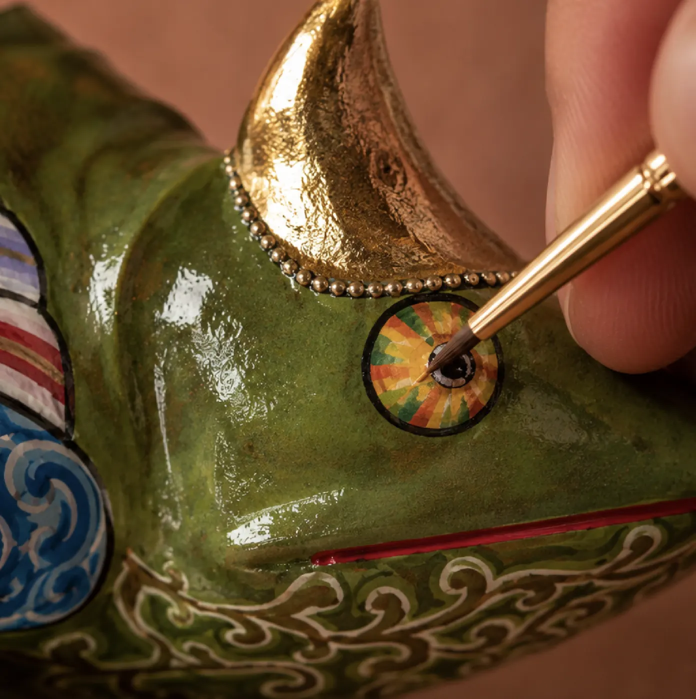 An artisan painting the eye of a Tom's figure with a fine brush